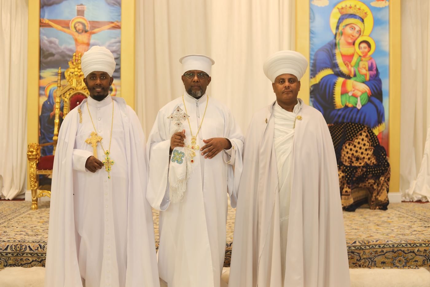 Three clergy of the parish in white vestments with hand crosses