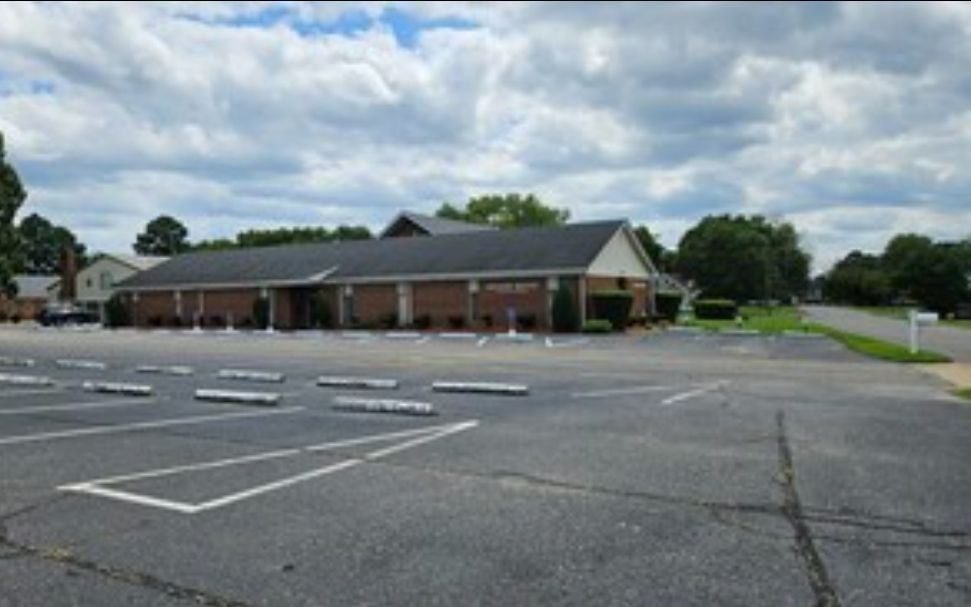 The church building, a brick hall with a pitched roof and a large parking lot