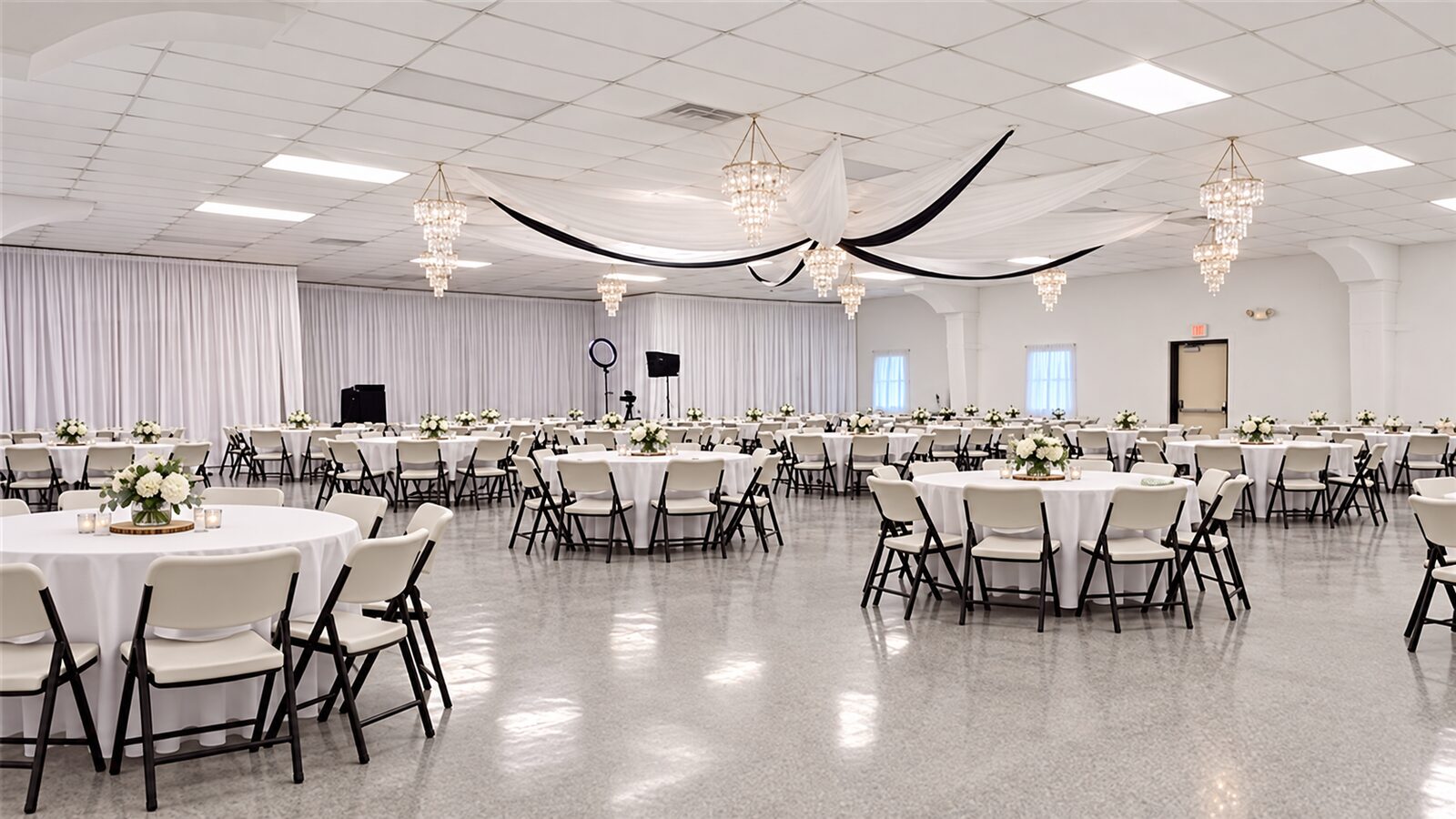 Inside the Debre Enqu Beata LeMariam event hall in Richmond, VA, set with round tables, white linens, chairs and chandeliers for a reception